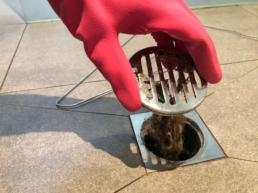Clearing the shower drain because it is clogged with hair
