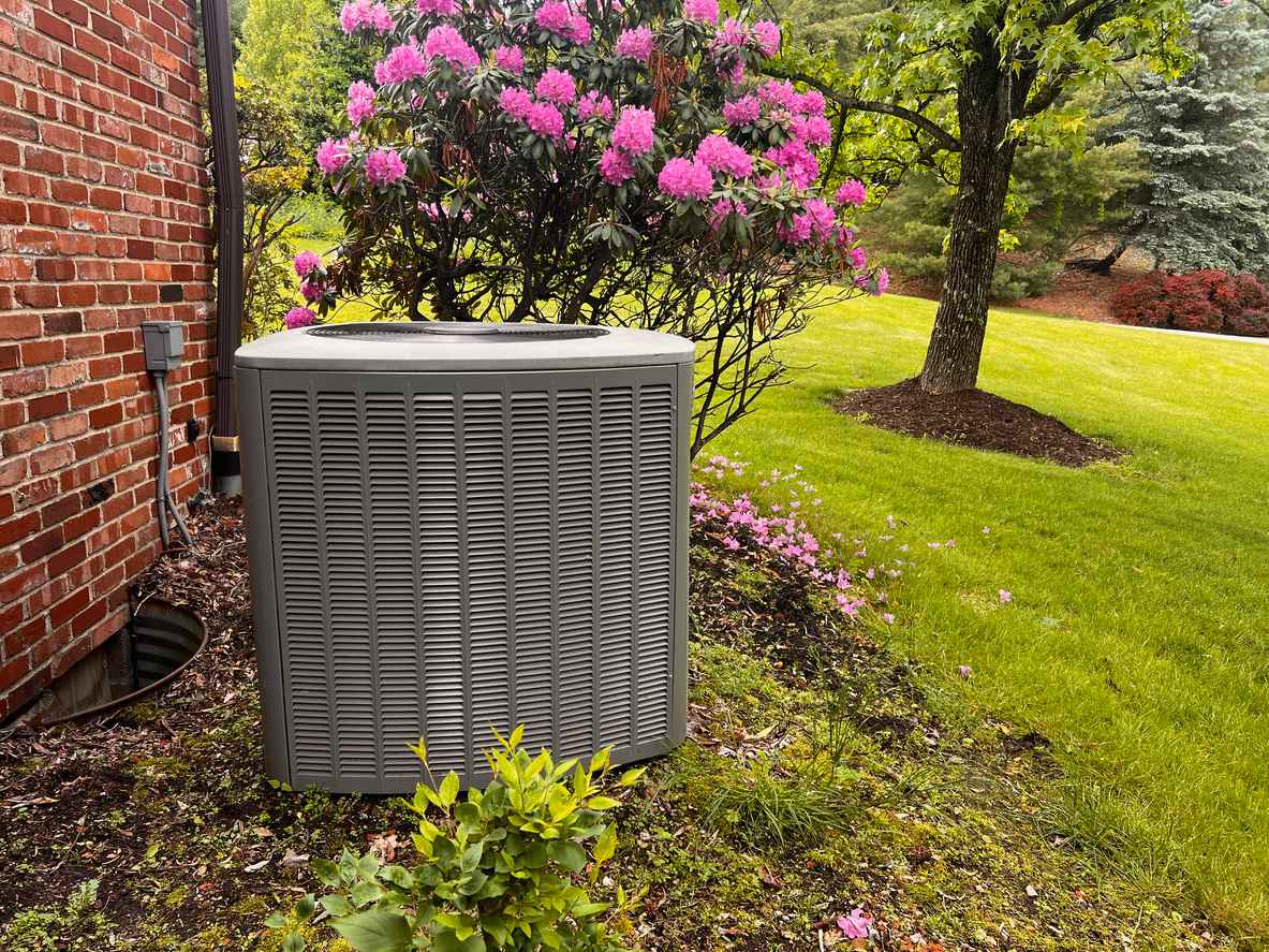 outdoor HVAC system with spring flowers surrounding it